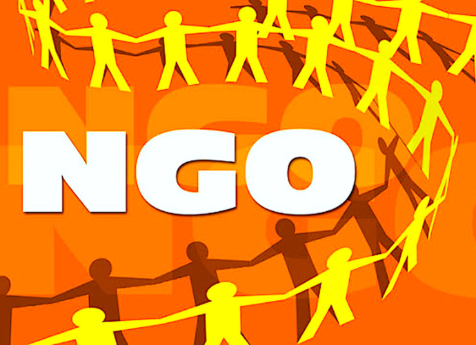 Biały napis na pomarańczowym tle litery NGO. Dookoła napisu zółte zarysy postaci trzymających się za ręce