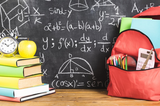 Zdjęcie przedstawia plecak z przyborami szkolnymi oraz podręczniki, jabłko i budzik na tle zapisanej tablicy szkolnej