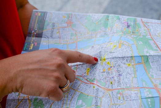 A person with a red shirt points at a city map indicating travel guidance. Perfect for tourism concepts.
